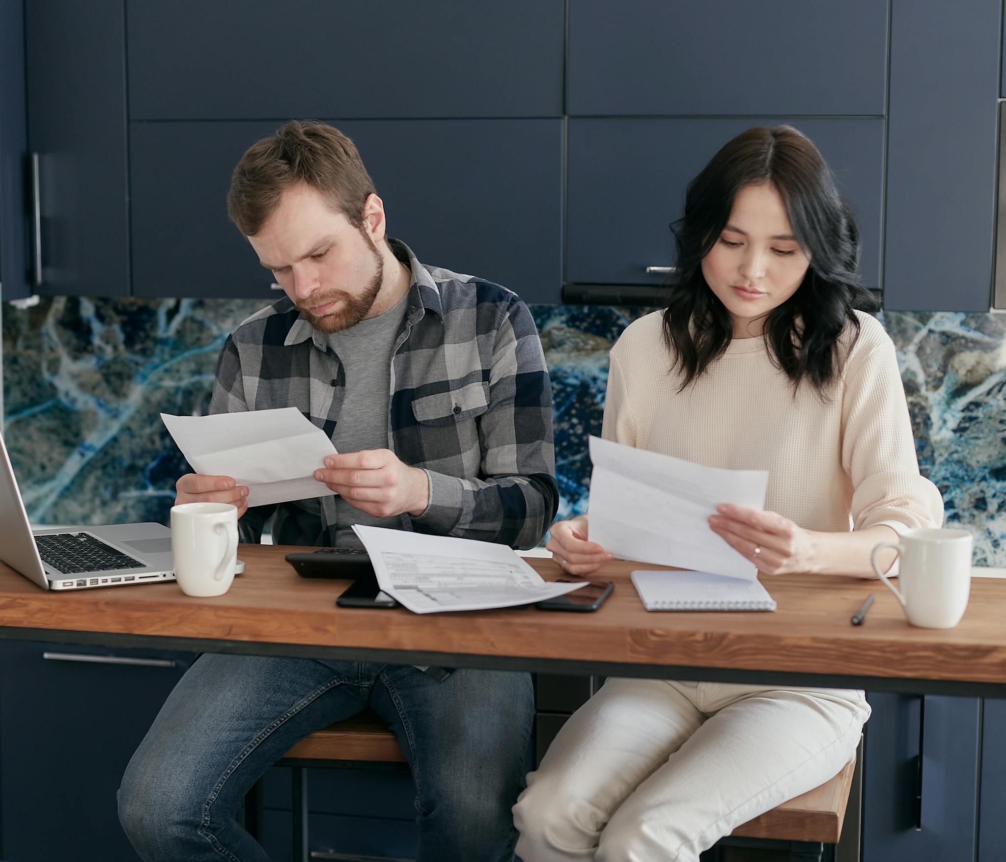 A couple reviewing financial documents at home, showcasing concern and focused collaboration.